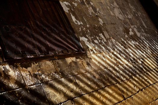 Rusty grilling on the window of an old stone wall