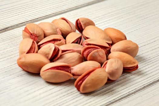 Clsoeup to small pile of Turkish red pistachios on white boards desk.