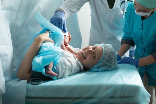 Mother holds newborn baby in hospital, seconds after birth.