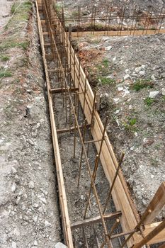 Fragment of reinforcement of the strip foundation, the trench is partially covered with earth