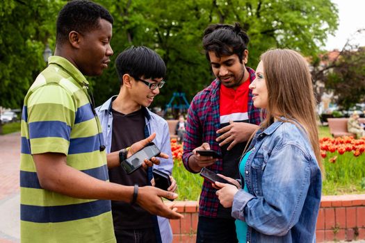 College students having great time together after lessons. Young people can't live without their smartphones, checking massages during meeting with friends. Gadgets addiction concept.