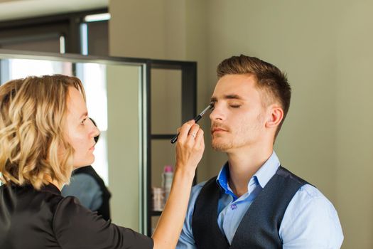 Make-up for man, make-up artist's hands near the male face