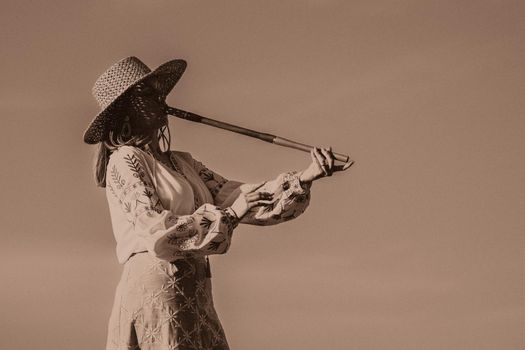 Woman plays on wooden flute - ukrainian telenka, tylynka. Retro toning. sepia. Folk music, sopilka concept. Musical instrument. Musician in traditional embroidered shirt - Vyshyvanka. quality photo