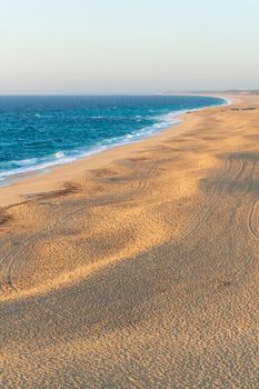 Deserted sandy beach of the atlantic ocean in the rays of the setting sun top view