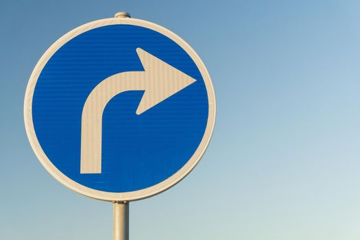 Road sign blue right turn signal on sky background close up