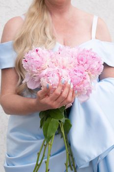 bride in a blue wedding dress with a bouquet of pink peonies, pastel paradise, floral background, complementary color combination. High quality photo