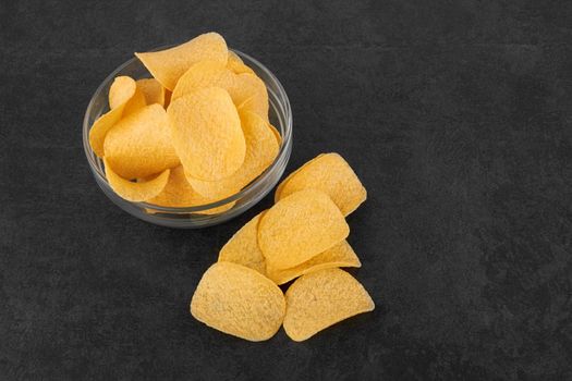 Potato chips on a stone black surface in a saucer