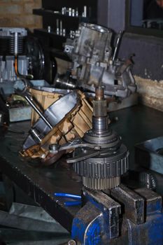 Engine transmission gear assembly being disassembled on workshop bench vice