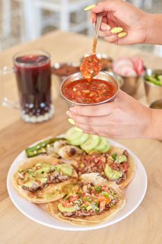 Girl eating delicious taco with salsa and a variety of toppings. Mexican taco with salsa, taco al pastor.