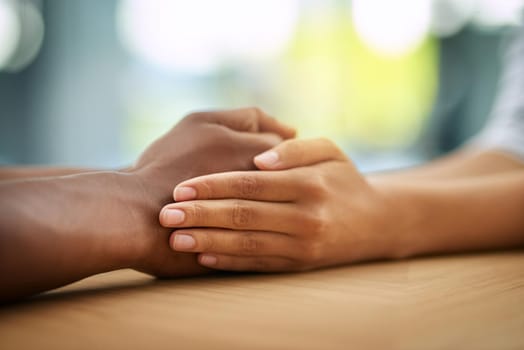 We are in this together. two unrecognizable people holding hands while being seated at a table inside during the day