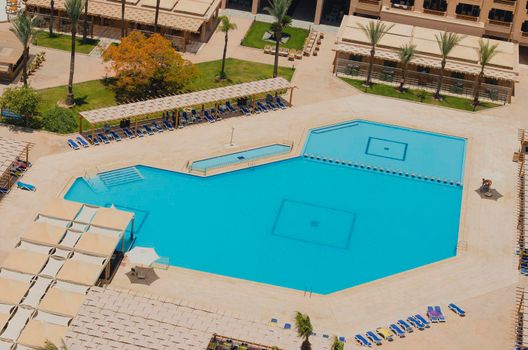 Aerial view of a large swimming pool in a luxury tropical hotel with sun loungers