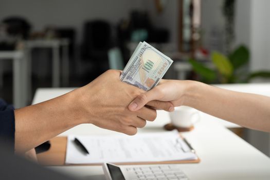 Businessmen making handshake with money in hands - bribery, corruption and venality concepts.