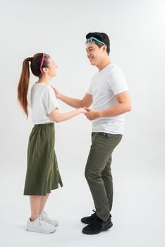 smiling young couple dancing and holding hands, isolated on white