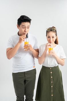 Happy young couple with glasses of orange juice isolated on a white background.