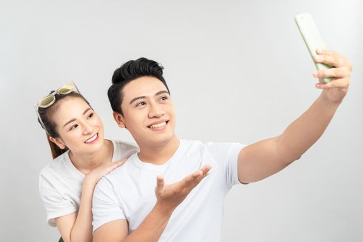 Funny young couple friends guy girl posing isolated on white background. Doing selfie shot on mobile phone