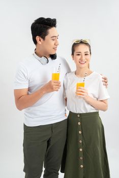 Young couple holding glasses of orange juice, isolated on white background