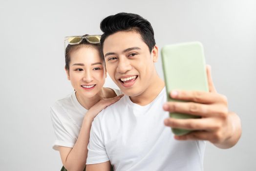 Funny young couple friends guy girl posing isolated on white background. Doing selfie shot on mobile phone