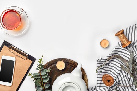 Still life with tea cup and the contents of a workspace composed. Different objects on white table. Flat lay. Top view. Copy space