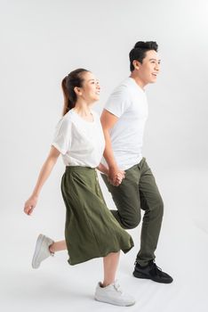 Young couple in casual clothes walking on white background