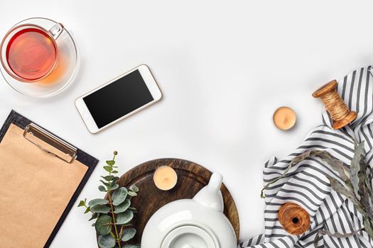 Still life with tea cup and the contents of a workspace composed. Different objects on white table. Flat lay. Top view. Copy space