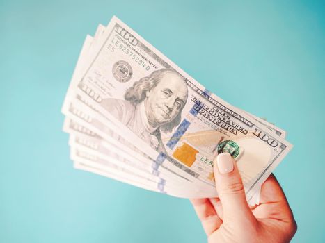 Woman's hand with money isolated on a blue background