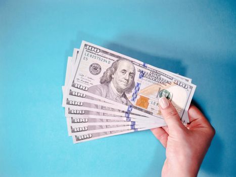 Woman's hand with money isolated on a blue background