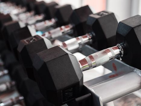 Rows of heavy metal dumbbells on rack in the gym or club. Weight Training Equipment. Sport and health concept.