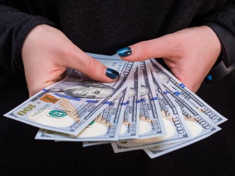 Woman hand with dollars isolated on black background. Girl counting money.