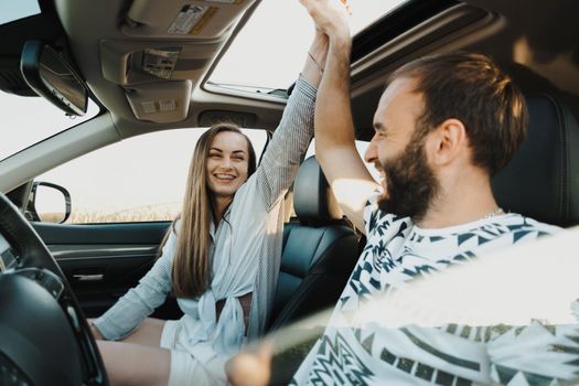 Happy middle-aged couple together on a road trip, caucasian woman and man having fun on vacation on SUV car