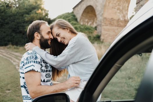 Caucasian man and woman hugging on hood of car, middle-aged couple enjoying road trip together