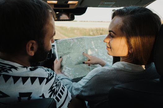 Middle aged couple on a road trip, caucasian man and woman planning next stop on map while sitting inside car