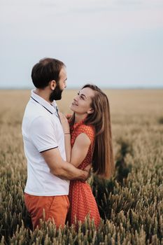 Happy middle-aged couple hugging in wheat field, caucasian cheerful woman and man in love standing together outdoors