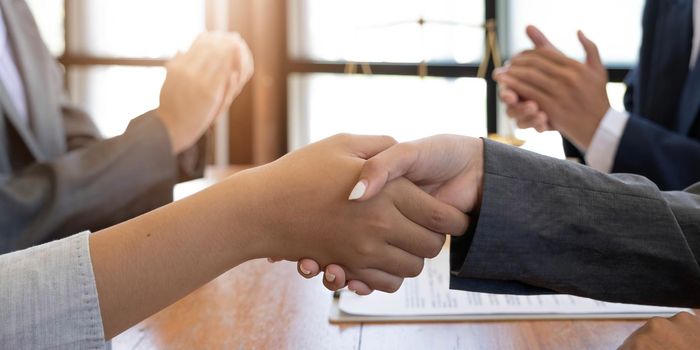 Businessman shaking hands to seal a deal with his partner lawyers or attorneys discussing a contract agreement.