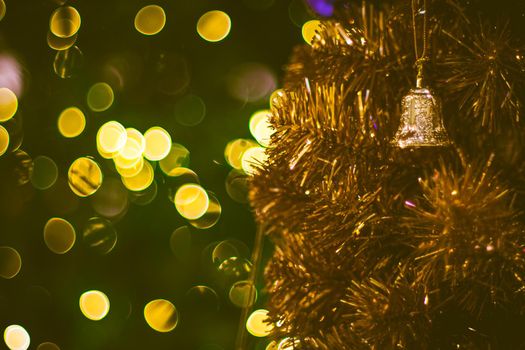 Christmas golden bell decoration on yellow background. Colorful blur bokeh background. Christmas background