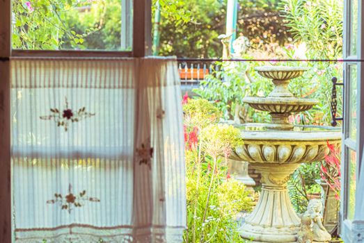 handmade white curtain with window view of fountain and  green from tree garden background