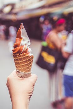 Hand holding melting ice cream waffle cone in hand on summer background