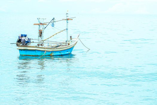 Small fishing boat floating in blue sea with blue sky