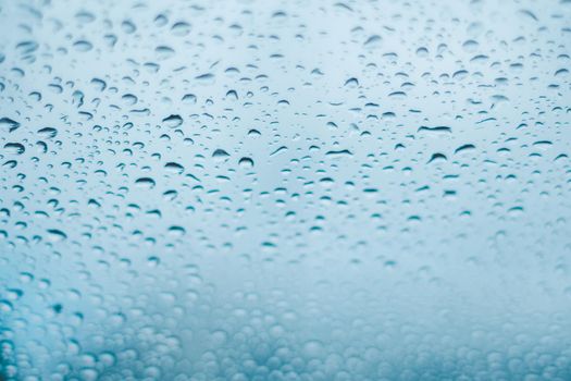 Raindrops on the window. Water droplets on glass. Blue tone