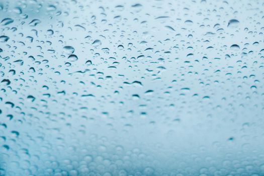 Raindrops on the window. Water droplets on glass. Blue tone