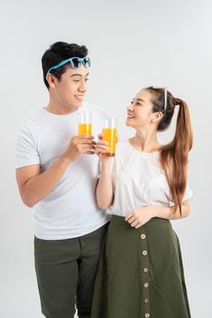 Happy young couple with glasses of orange juice isolated on a white background.