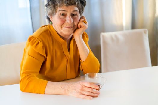 A portrait of a laughing, smiling elderly woman with gray hair and wrinkles on her face, but young at heart and leading an active lifestyle. Happy pensioner is pretty posing in her cozy home.