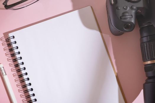 Fragment of notebook, glasses and SLR camera on desktop top view. Learning photography, blogging concept.