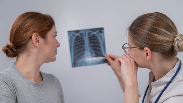 The doctor consults a caucasian woman and comments on the x-ray of the lungs