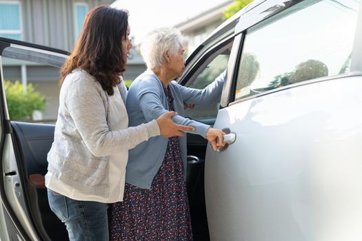 Caregiver help Asian senior or elderly old lady woman patient get to her car, healthy strong medical concept.