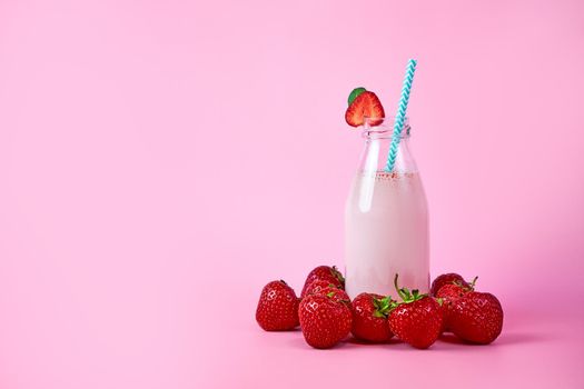 Strawberry smoothie or milkshake in glass jar with berries on pink background. Healthy summer drink.
