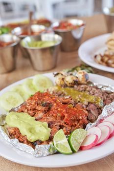 variety of delicious typical mexican food and ingredients such as salsas, red, green, guacamole, lemon, tomato and onion.