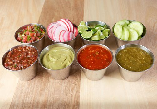 variety of delicious typical mexican food and ingredients such as salsas, red, green, guacamole, lemon, tomato and onion.