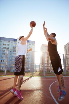 Two guys jump stretch to the ball on the basketball court.