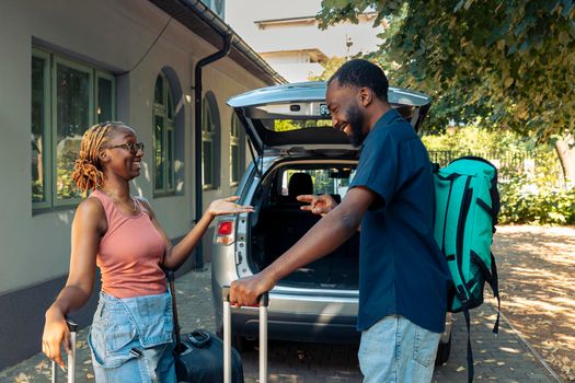 African american partners loading suitcase in trunk, leaving together on holiday vacation. Man and woman preparing to travel on adventure trip with luggage and baggage by vehicle.