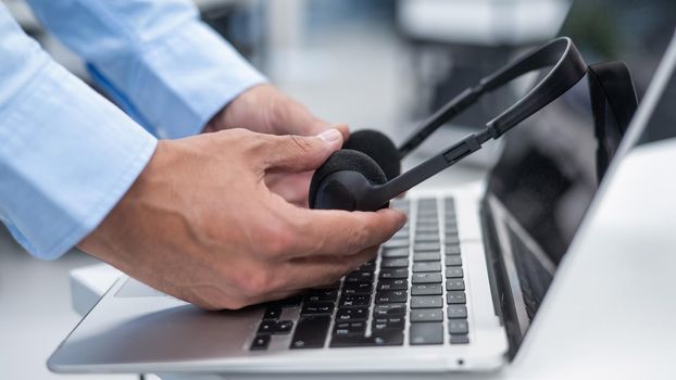 A man puts a headset on a laptop keyboard in the office